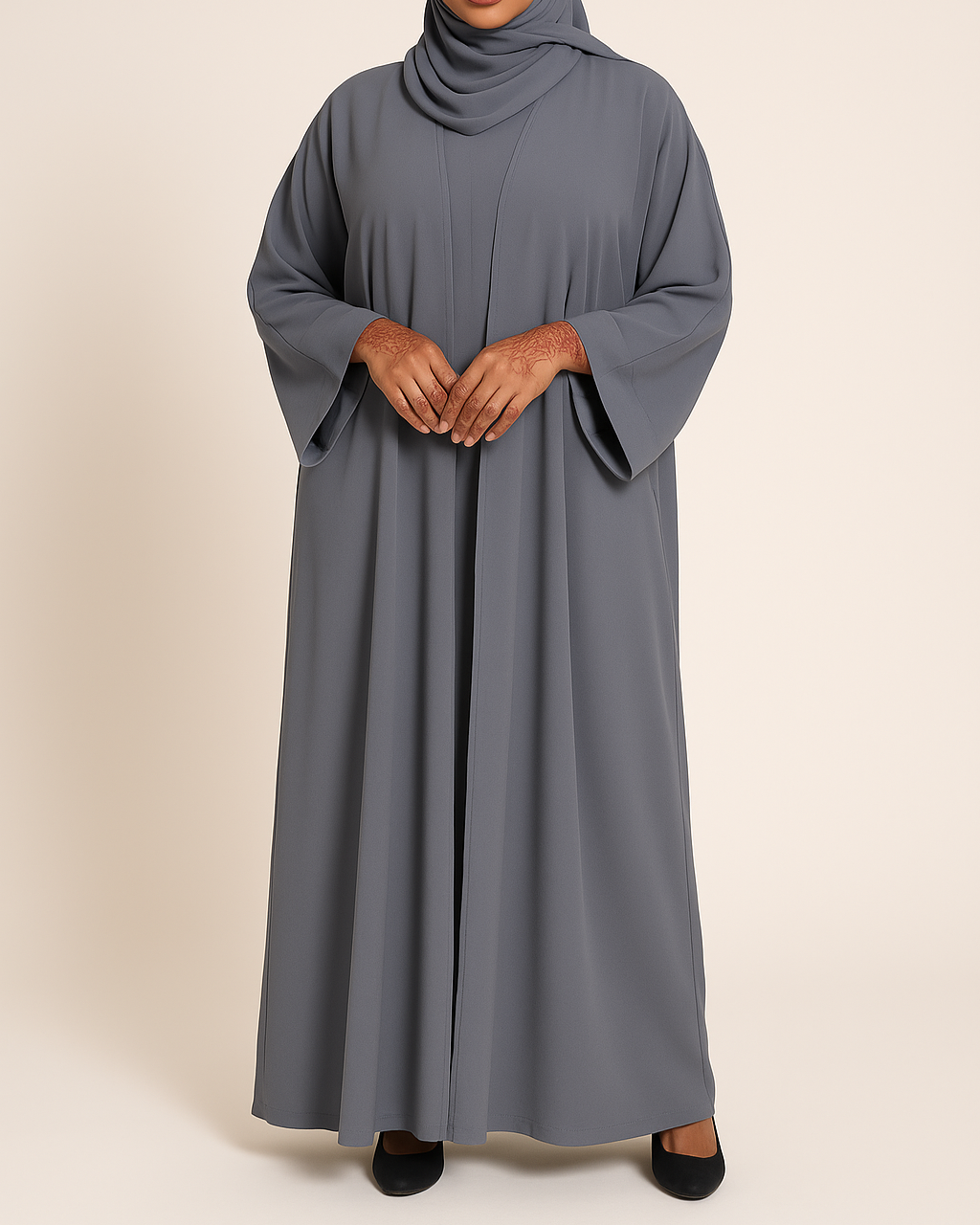 Woman wearing a gray abaya and hijab on a beige background
